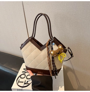 Detailansicht der gesteppten beigen Stofftasche mit Lederbesatz und Bärenanhänger