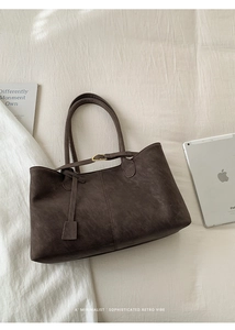 Detail of dark brown tote bag showing matte leather texture and metal buckle closure