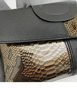 Close-up of litchi grain leather and gold snake pattern texture with stitching details