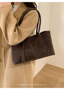 Detail view of large dark brown suede tote bag worn with a khaki wool coat