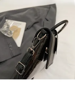 Close-up of durable silver D-ring and lobster clasp on black faux crocodile leather bag