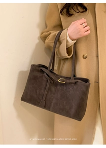 Detail of dark brown tote bag with gold ring hardware on a camel wool coat background