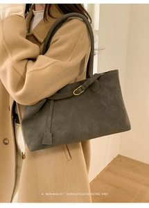 Deep gray matte tote bag styled on model with camel wool coat in minimalist interior