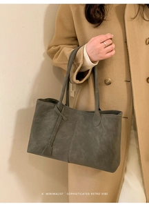 Detail of dark grey oversized tote bag with vertical stitching on camel coat model