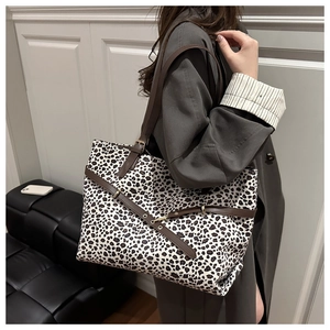 Détail du grand sac cabas léopard avec bandoulière en cuir marron et boucles dorées