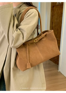 Detail of brown suede tote bag with golden buckle and sophisticated retro stitching