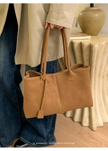 Close-up of caramel faux leather tote bag showing matte texture and retro strap details