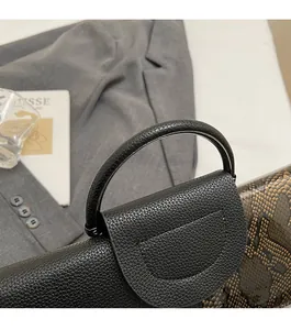 Detail of elegant black crocodile pattern handbag with circular handle and smooth texture