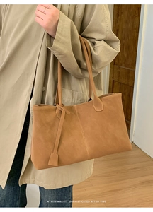 Detail of retro brown tote bag with contrast stitching and thin leather shoulder straps