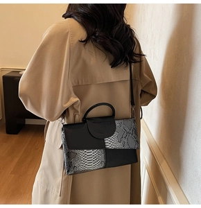 Detail view of the snakeskin and black leather panel design on this crossbody handbag