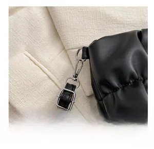 Detail of silver metallic hook and buckle on a black pleated faux leather shoulder bag