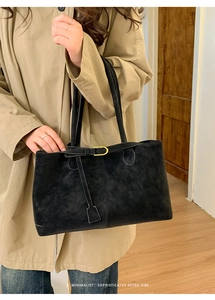 Minimalist black suede tote bag detail with slim leather buckle and retro shoulder strap