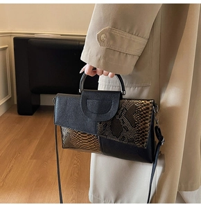Detail of elegant crocodile texture stitching and metal handle on crossbody handbag