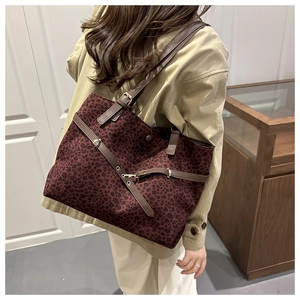 Détail du cabas léopard bordeaux avec lanières marron et boucles métalliques dorées