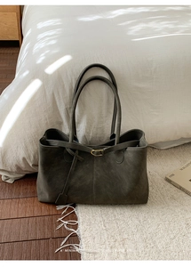 Close-up of a large grey leather tote bag on a white rug with a retro aesthetic