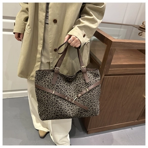 Détail d'un sac cabas léopard avec lanières en cuir marron et boucle métallique élégante