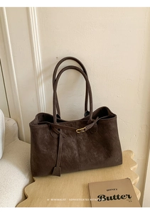 Detail of dark brown tote bag with matte leather texture and gold metal accents