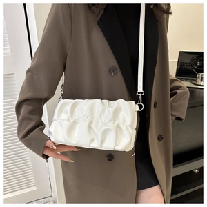Detail of white pleated cloud bag with soft leather texture and adjustable shoulder strap