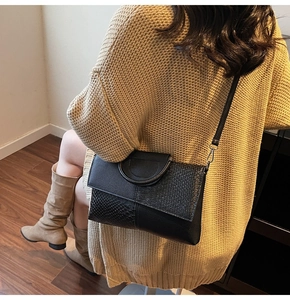 Detail view of black crocodile pattern leather bag with a stylish circular metal handle