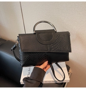 Close-up of black crocodile pattern leather handbag with silver metal handle