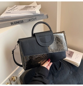 Detail of black leather handbag featuring snake pattern patchwork and silver-tone hardware