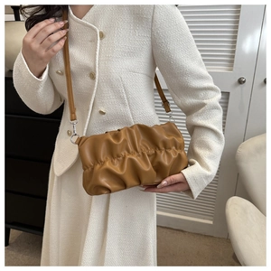 Detail of caramel pleated cloud bag with soft leather texture and silver metal hooks