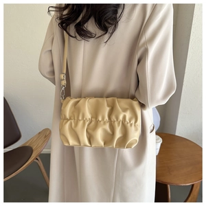 Close-up of beige pleated shoulder bag with soft leather texture and adjustable strap