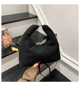 Close-up of black fuzzy faux shearling hobo bag texture with stylish crescent design