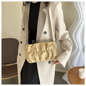 Detail of beige pleated cloud bag with soft leather texture and slim shoulder strap