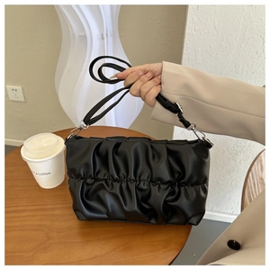 Detail of black pleated cloud bag showing fine faux leather folds and shoulder strap