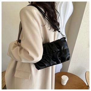 Detailed view of black pleated cloud bag texture with silver metal hooks and PU leather finish