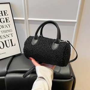 Black plush shearling cylinder bowling bag with leather strap shown in hand
