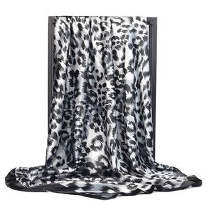Detailed view of leopard print satin scarf featuring black borders and elegant draping