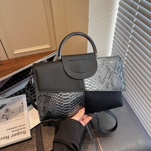 Elegant crocodile pattern handbag with metal handle and shoulder strap in urban office setting