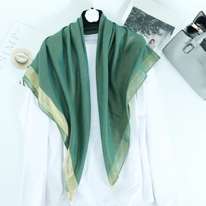 Detailed view of dark green scarf with golden lurex thread and wide metallic edge finish