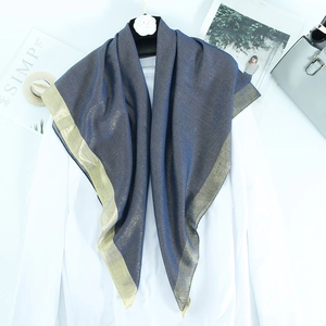 Detail of navy blue lightweight scarf with metallic gold thread border on a stylish display