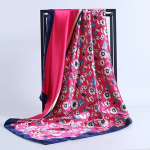 Close-up of a floral satin square scarf with rose pink base and blue floral patterns