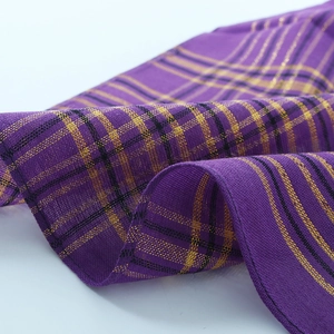 Vue détaillée du tissu à carreaux violet foncé avec fil doré et bordure noire brodée