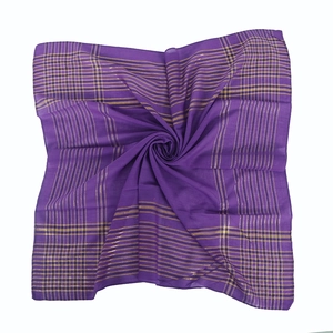 Gros plan d'un châle en coton violet avec fils dorés disposé en spirale sur fond blanc