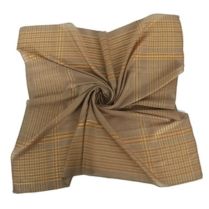 Détail d'une écharpe à carreaux marron avec fils dorés pliée en forme de spirale