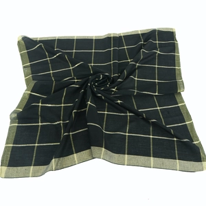 Macro detail of black and gold checkered scarf fabric showing soft spiral draping texture
