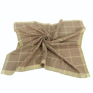 Macro detail of plaid cotton scarf with golden thread embroidery and hemmed edges