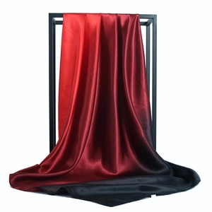 Glossy red to black gradient satin silk scarf draped on a minimalist display stand