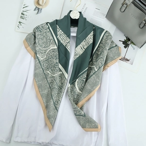 Foulard quadrato in seta verde bosco con motivi paisley drappeggiato su camicetta