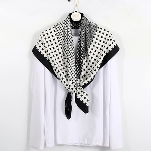 Detail of a black and white geometric silk scarf draped on a white shirt and hanger