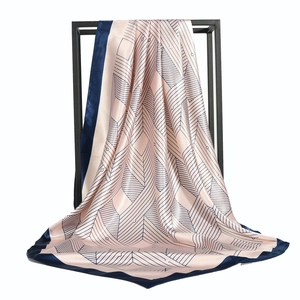 Geometric diamond print satin silk scarf draped elegantly over a black display stand