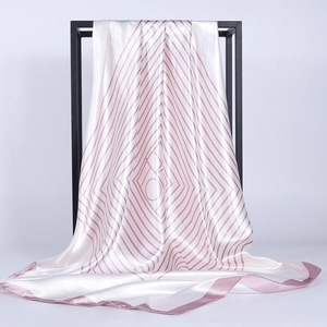 Dettaglio del foulard in raso a righe perlate drappeggiato su un supporto in metallo minimalista