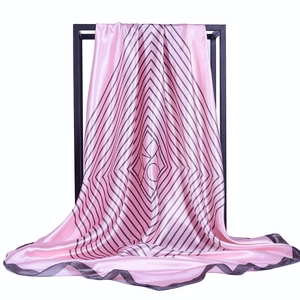 Foulard quadrato in raso rosa con righe geometriche nere appeso a una cornice nera