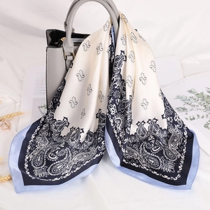 Elegant paisley print silk square scarf draped on a luxury handbag for a chic look