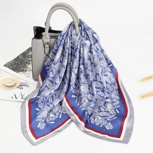 Royal blue paisley silk scarf with burgundy border draped over a grey leather handbag